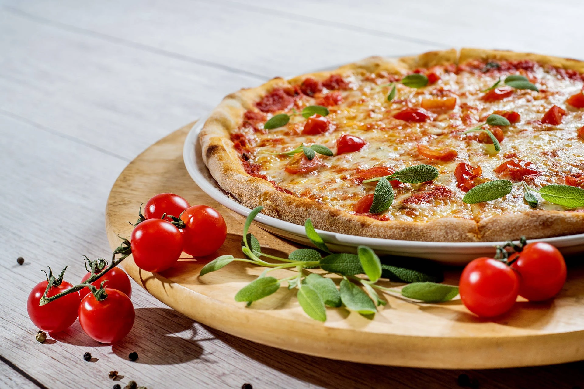Freshly baked pizza served with tomatoes and fresh basil