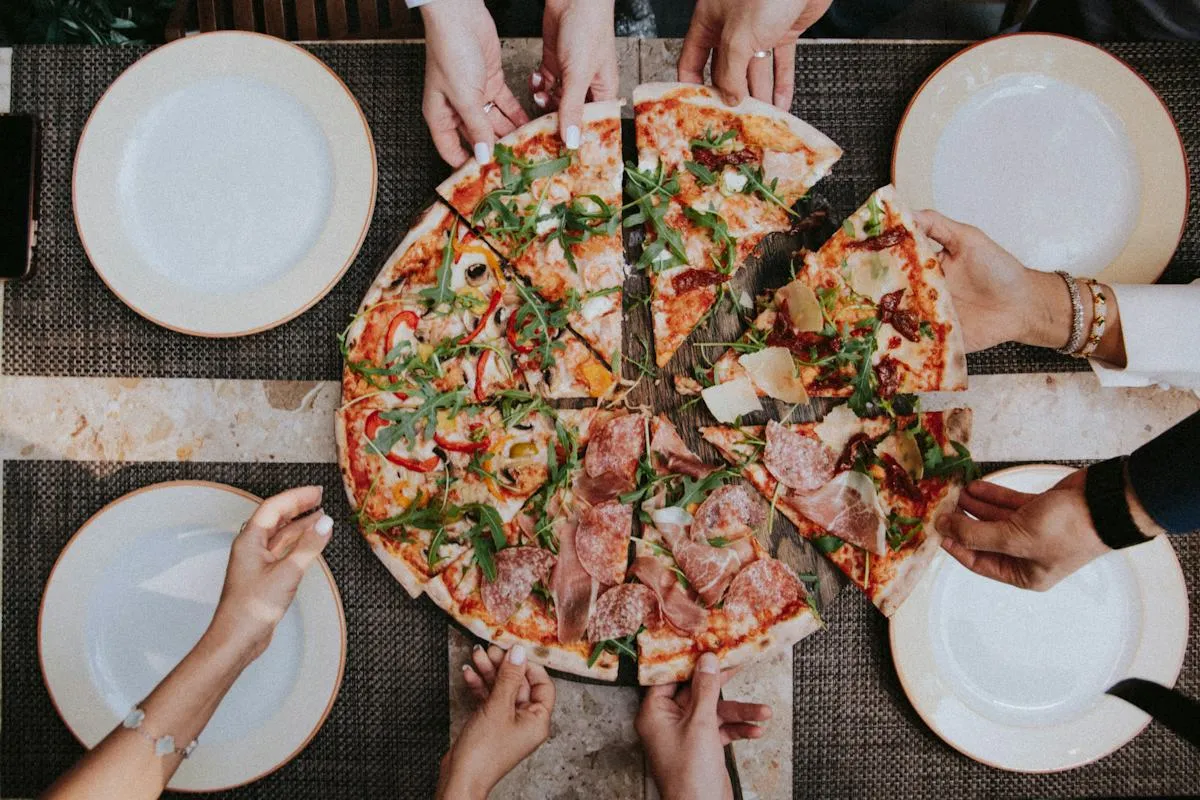 Friends sharing fresh pizza at a table